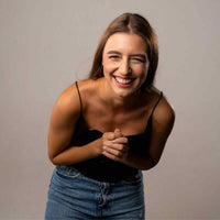 Thumbnail for Laughing woman wearing a black top and jeans, exuding joy and warmth, showcasing a cheerful demeanor.
