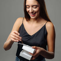 Thumbnail for Woman joyfully unboxing the Sunflower Photo Necklace from Brother & Sisters, showcasing personalized jewelry.