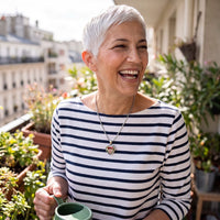 Thumbnail for Woman laughing on her balcony, wearing the silver secret heart photo necklace | SKU: TPH-CHTN-SILVER-SMALL