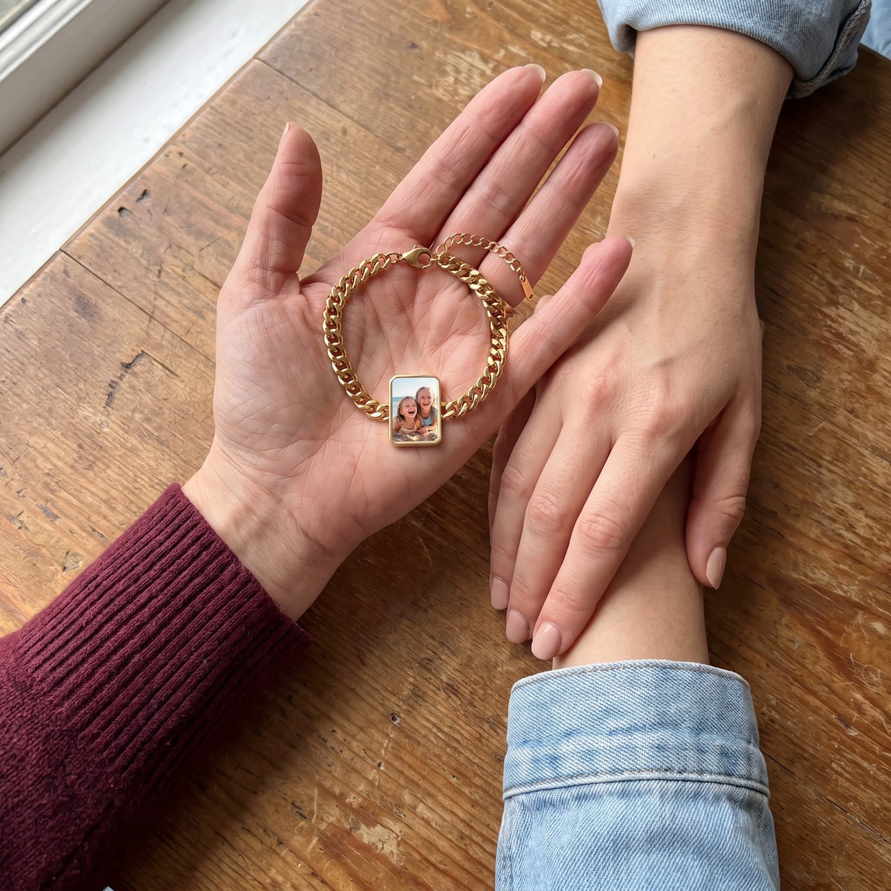 The gold cushion-cut photo bracelet in her palm beside her sister's hand, showing a photo of two little sisters at the beach | SKU: TPH-CUSB-GOLD