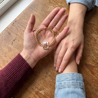Thumbnail for The gold cushion-cut photo bracelet in her palm beside her sister's hand, showing a photo of two little sisters at the beach | SKU: TPH-CUSB-GOLD