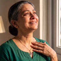 Thumbnail for Woman in a green blouse moved to tears, her hand near the gold secret drop photo necklace | SKU: TPH-DRPN-GOLD